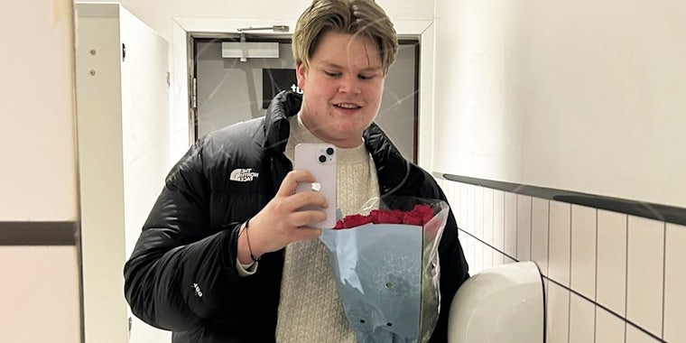 Man taking selfie with bouquet of roses in bathroom